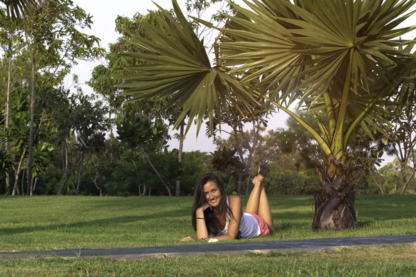 Mujer joven descansando tendida en la hierba en el parque — Foto de Stock