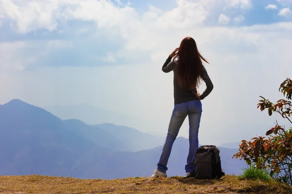 Vrouw reiziger met rugzak op zoek op het berglandschap en hemel — Stockfoto