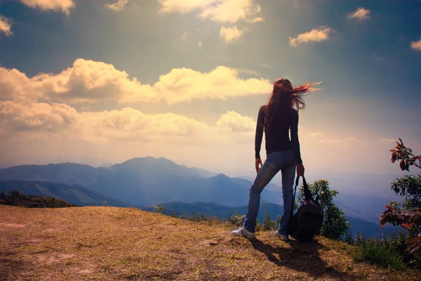 Vrouw reiziger met rugzak kijken naar berglandschap en hemel in avond tijd — Stockfoto