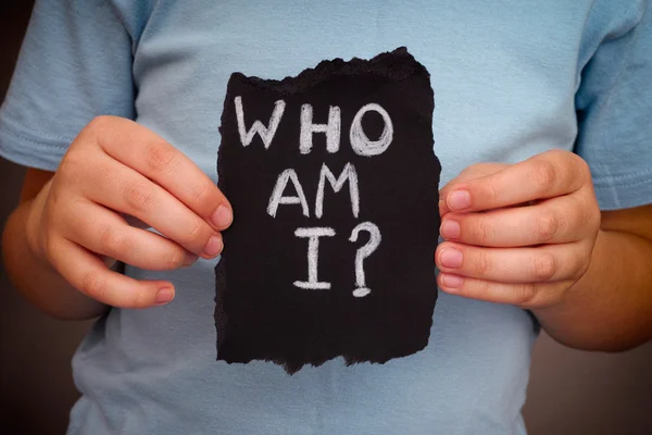 Child holds piece of black paper with question Who am I? — Stock Photo, Image