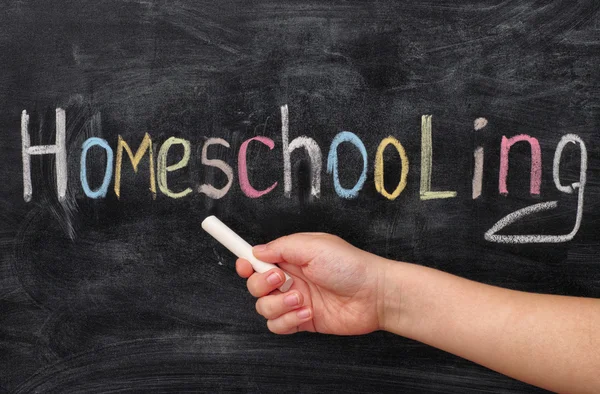 Hausaufgabenbetreuung. Kind zeigt auf Wort Homeschooling auf Tafel. — Stockfoto