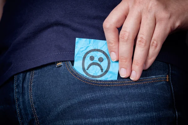 Womans hand takes out paper note with sad face from pocket of he — Stock Photo, Image