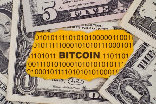 Piece of paper with the word Bitcoin against computer keyboard