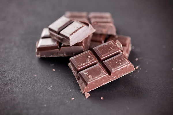 Pedaços de chocolate em um fundo preto — Fotografia de Stock