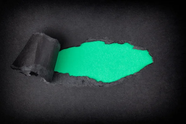 Зеленый бумажный фон появляется за разорванной черной бумагой — стоковое фото