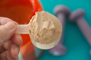 Elinde bir kepçe çikolatalı soya proteini izolasyon tozu tutan adam. Kapat..