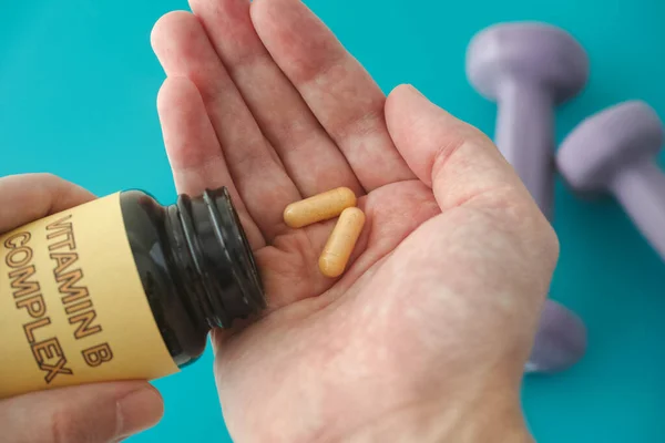 Person taking out Vitamin B Complex pills out of a bottle. Close up.