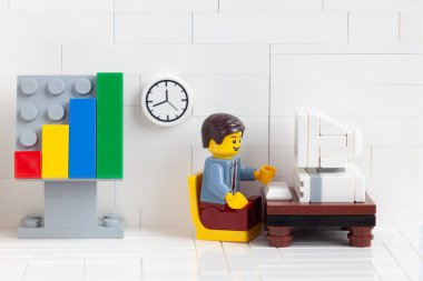 Tambov, Rusya Federasyonu - 3 Ocak 2021 Lego iş adamı minyatür bir bilgisayar başında oturuyor ve üzerinde çalışıyor.