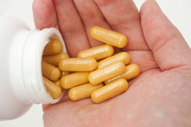 Şişeden Boswellia kapsüllerini çıkaran kişi. Kapat..