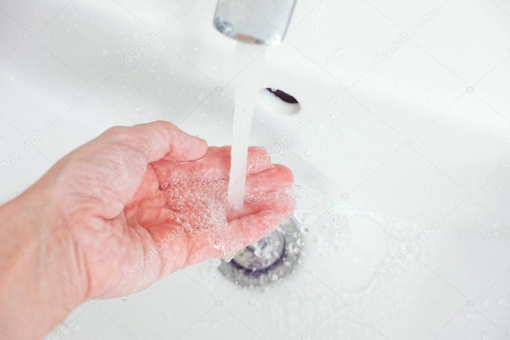 A man washing his hand with tap water. Close up.