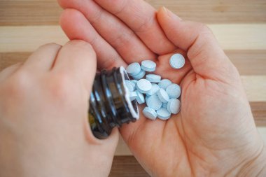 Şişeden bakır tabletleri çıkaran bir kadın. Kapat..