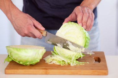 Kesme tahtasında lahana kesen bir adam. Kapat..