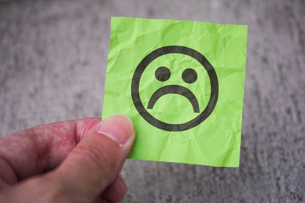 一个人手里拿着一张绿色的字条 手里拿着一张悲伤的脸 靠近点 — 图库照片