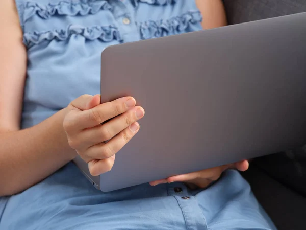 A woman watching a video on a laptop while sitting on a couch. Close up.