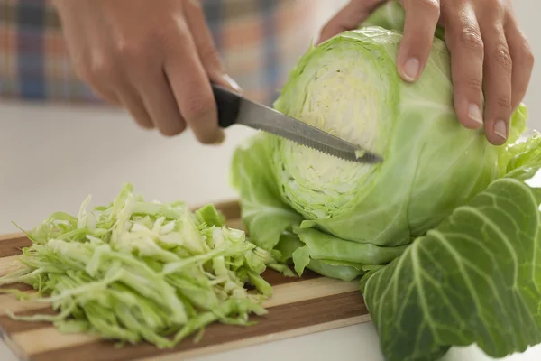 Woman cuts cabbage on cutting board in kitchen — Stock Image Woman cuts cabbage on cutting board in kitchen Royalty Free Stock Images