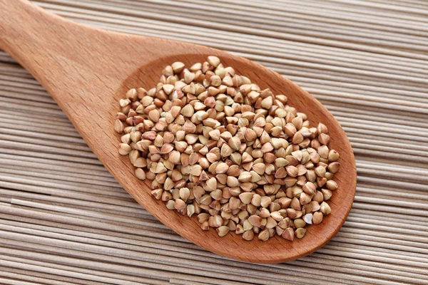 Buckwheat in a wooden spoon on soba noodles background — Stock Photo, Image