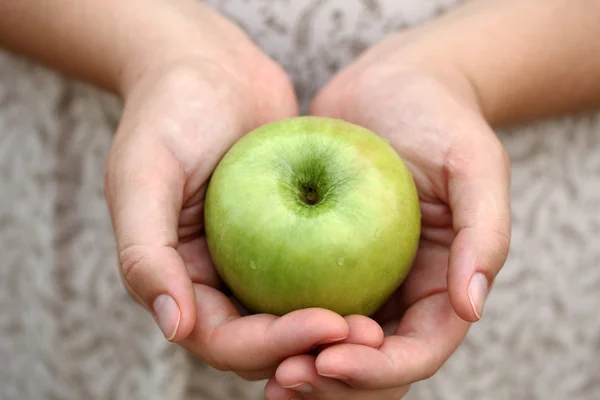 Las manos de una mujer sosteniendo una manzana verde — Foto de Stock