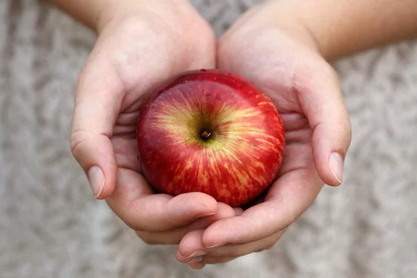 Les mains d'une femme tenant une pomme rouge — Photo