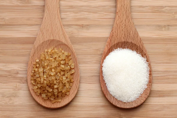 White and brown sugar in a wooden spoons — Stock Photo, Image