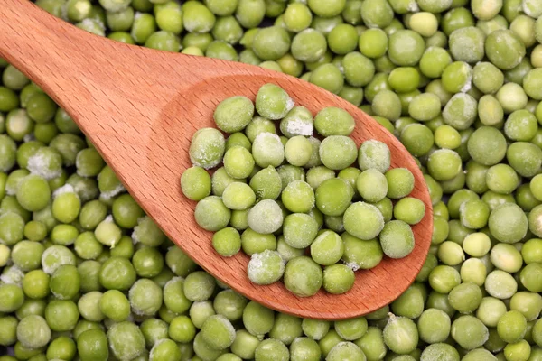 Guisantes verdes congelados en una cuchara de madera —  Fotos de Stock