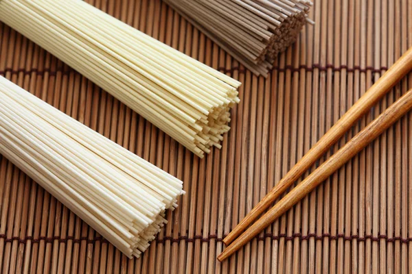 Fideos japoneses con palillos en servilleta de bambú —  Fotos de Stock