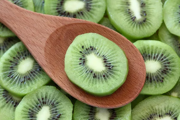 Kiwi slice in a wooden spoon — Stock Photo, Image