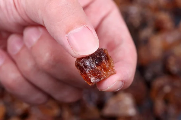 Rock cane sugar in the fingers — Stock Photo, Image