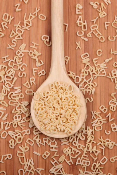 Rohe Buchstabensuppe Nudeln in einem Holzlöffel — Stockfoto