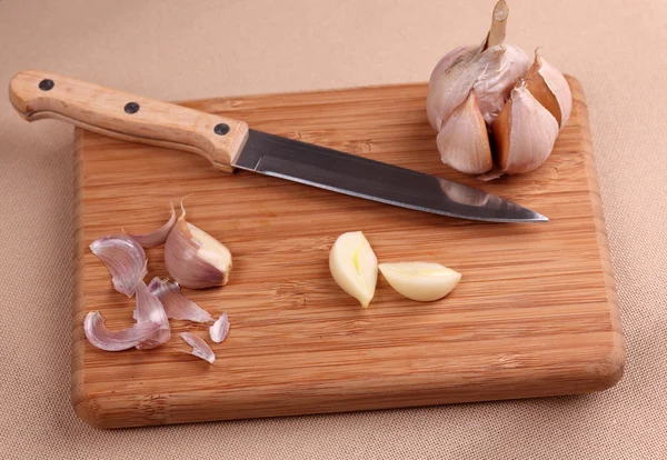 Garlic and knife on cutting board — Stock Photo, Image