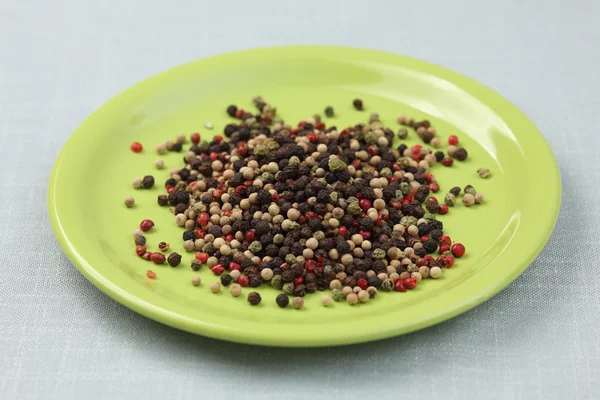 Mélange de grains de poivre sur une assiette verte — Photo