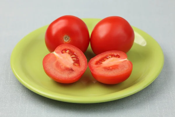 Rote frische Tomaten auf einem grünen Teller — Stockfoto