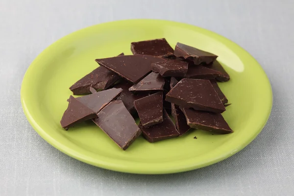 Pedazos de chocolate en un plato verde — Foto de Stock