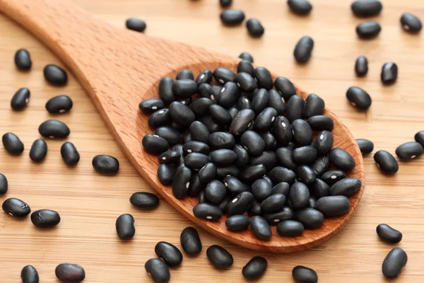 Black beans in a wooden spoon — Stock Photo, Image