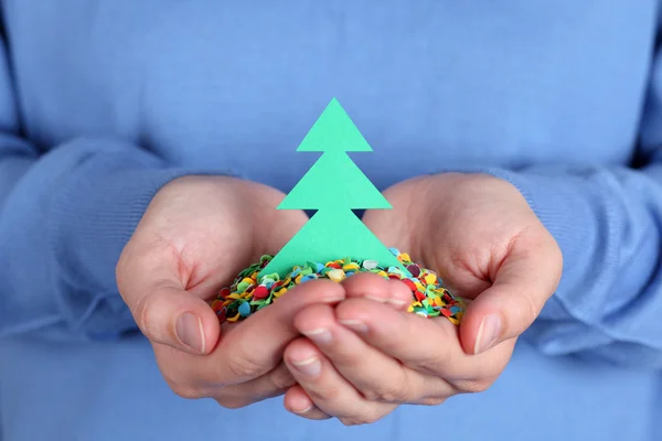 Woman holding a paper Christmas Tree with confetti in her hands — Stock Photo, Image