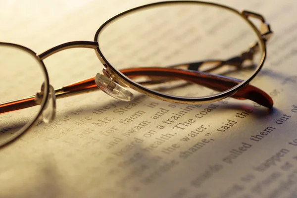 Öppna boken och läsglasögon — Stockfoto