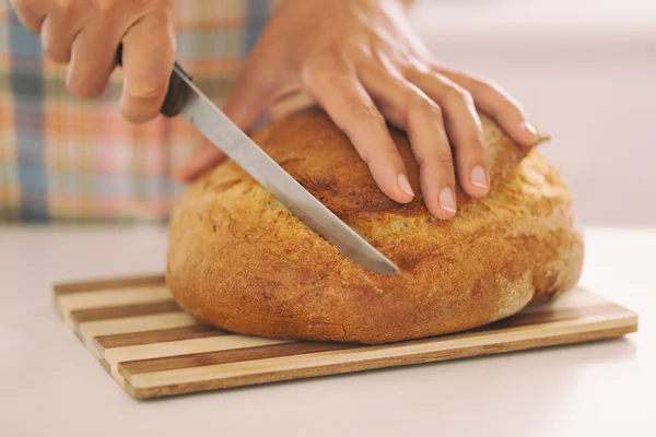 Woman's hands slicing bread — Stock Photo, Image