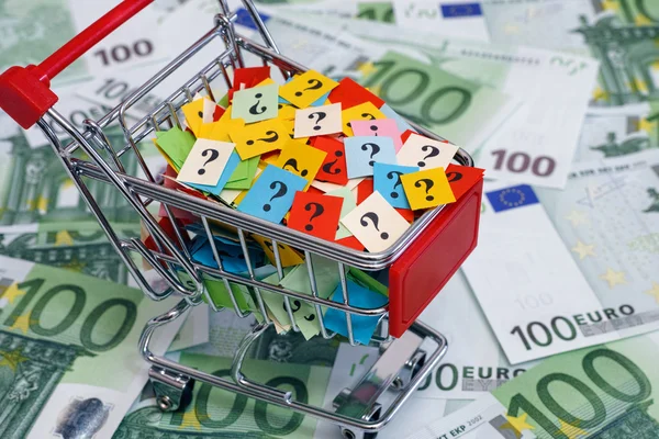 Nákupní košík s otazníky na sto euro bankovky — Stock fotografie
