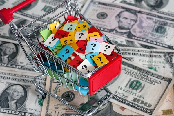 Winkelwagen met vraagtekens over dollar biljetten — Stockfoto