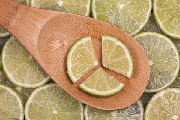 Lime slices in a wooden spoon — Stock Photo, Image