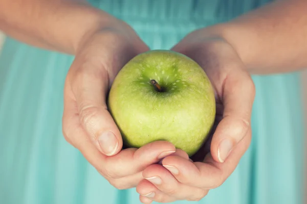 Les mains d'une femme tenant une pomme verte — Photo