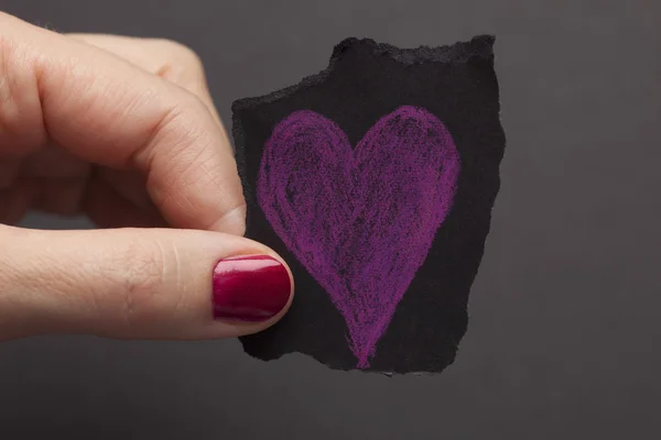 Pezzo di carta strappato nero con forma di cuore viola in han della donna — Foto Stock