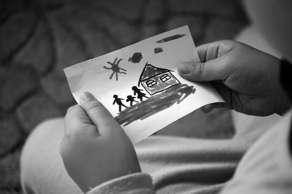 Niño sostiene una casa dibujada con la familia — Foto de Stock