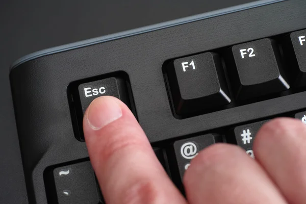 Finger pushing Esc key on black keyboard — Stock Photo, Image