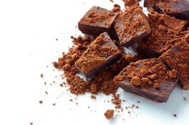 Broken dark chocolate with cocoa powder