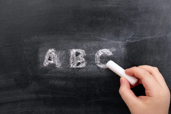 Childs hand writing ABC on blackboard — Stock Photo, Image