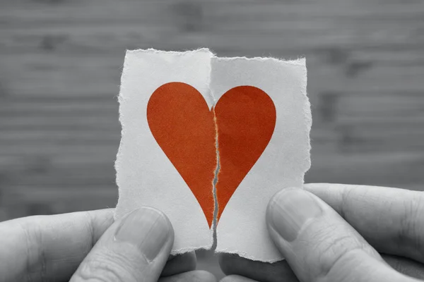 Man holds red broken paper heart in his hands — Stock Photo, Image