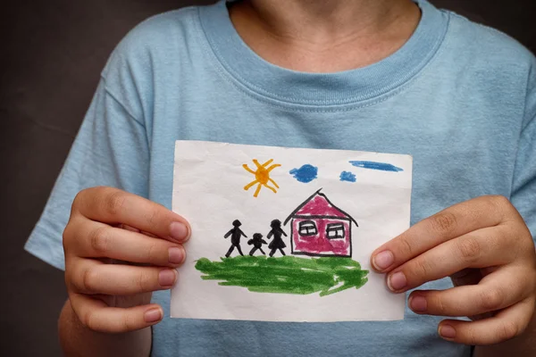 Niño sostiene una casa dibujada con la familia — Foto de Stock