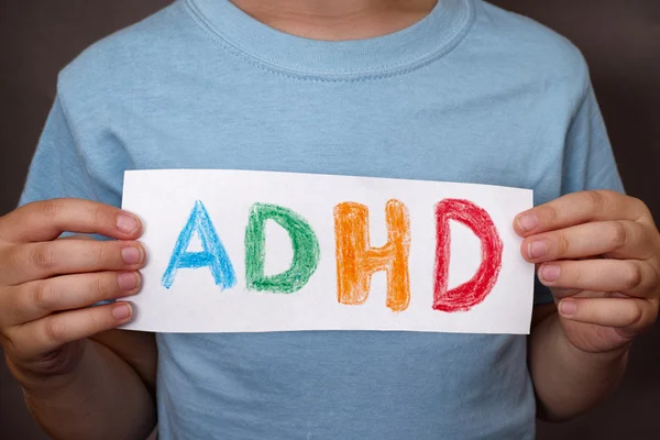 Jonge jongen houdt Adhd tekst geschreven op vel papier — Stockfoto