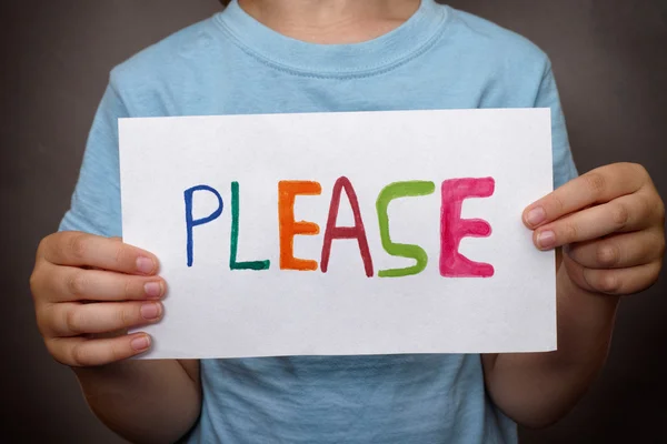 Young boy holds paper note with word Please — Stock Photo, Image