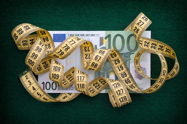 Fita métrica com mais de cem notas de euro sobre fundo verde — Fotografia de Stock